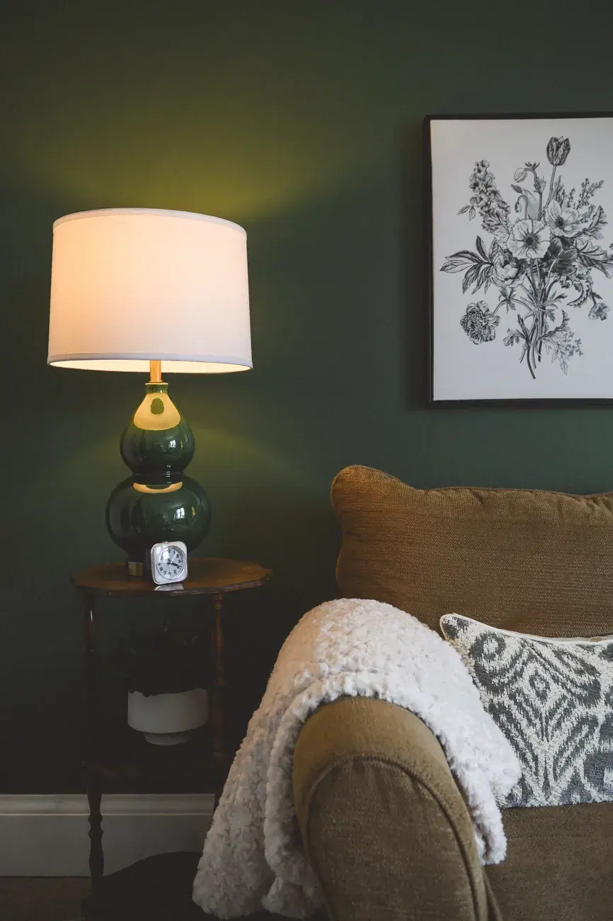 A calm corner of the St. Agatha office: a softly lit lamp on a side table beside a comfortable armchair with a throw.
